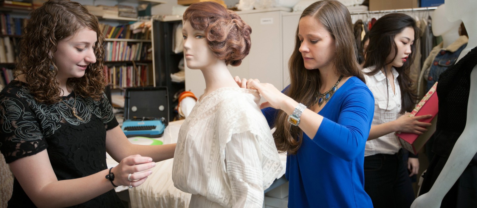 Students and professor dress a mannequin in a white dress