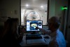 two people viewing a brain scan on a computer with an MRI machine in the background