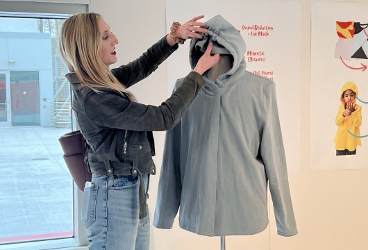 Julia DeNey ’20 demonstrates the hidden functions of a hooded sweatshirt in the exhibit.