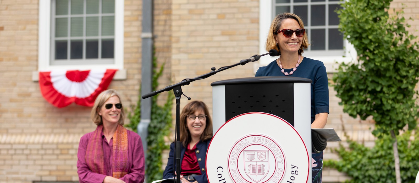 woman speaking at a lectern with Cornell University seal