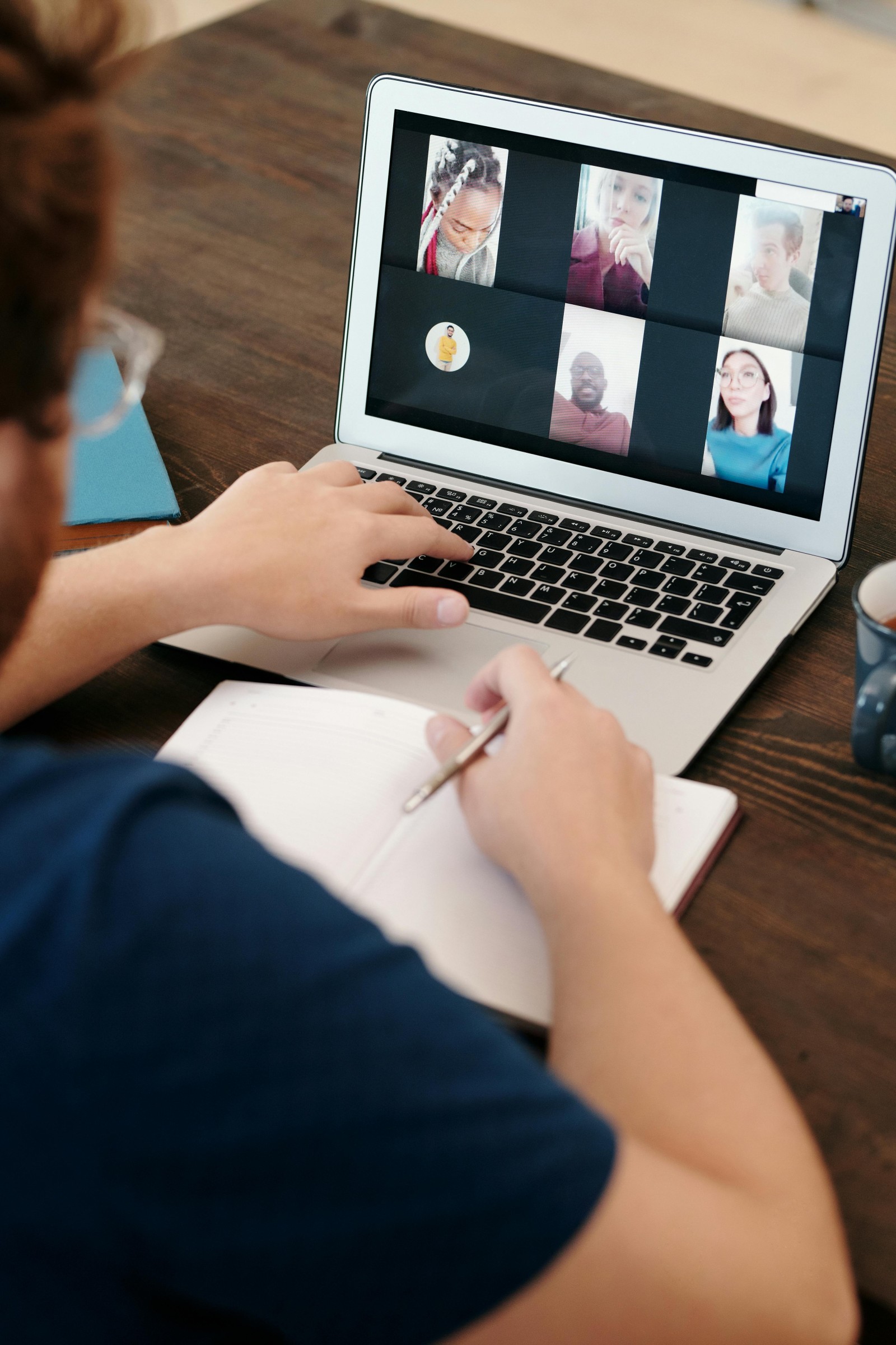 person looking at a laptop screen with images of others in an online meeting