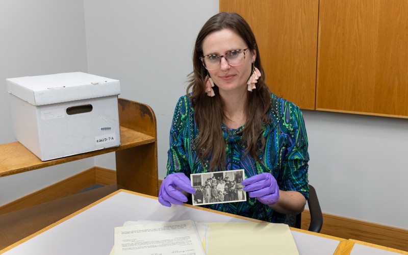 woman in purple gloves holds an old photograph