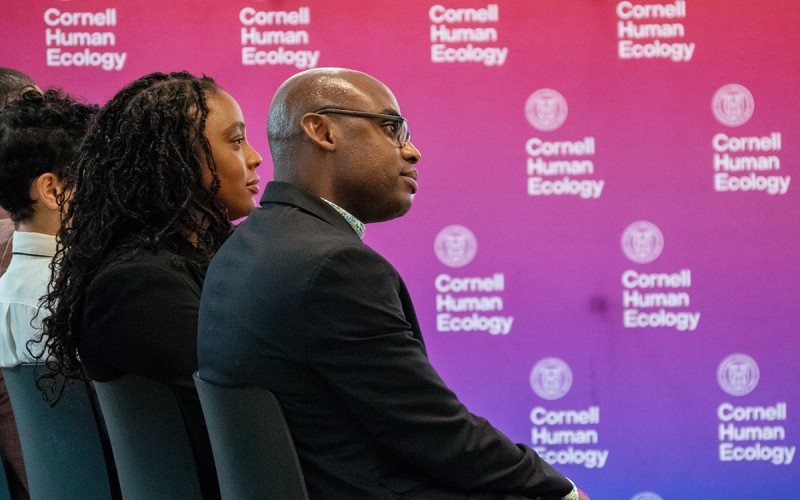 row of people in profile with a backgound of a purple and red pattern with the Cornell Human Ecology logo on it