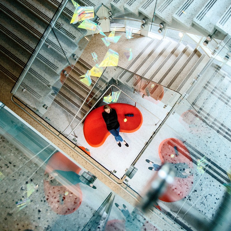 overhead view looking down a stairwell at a person on a red couch