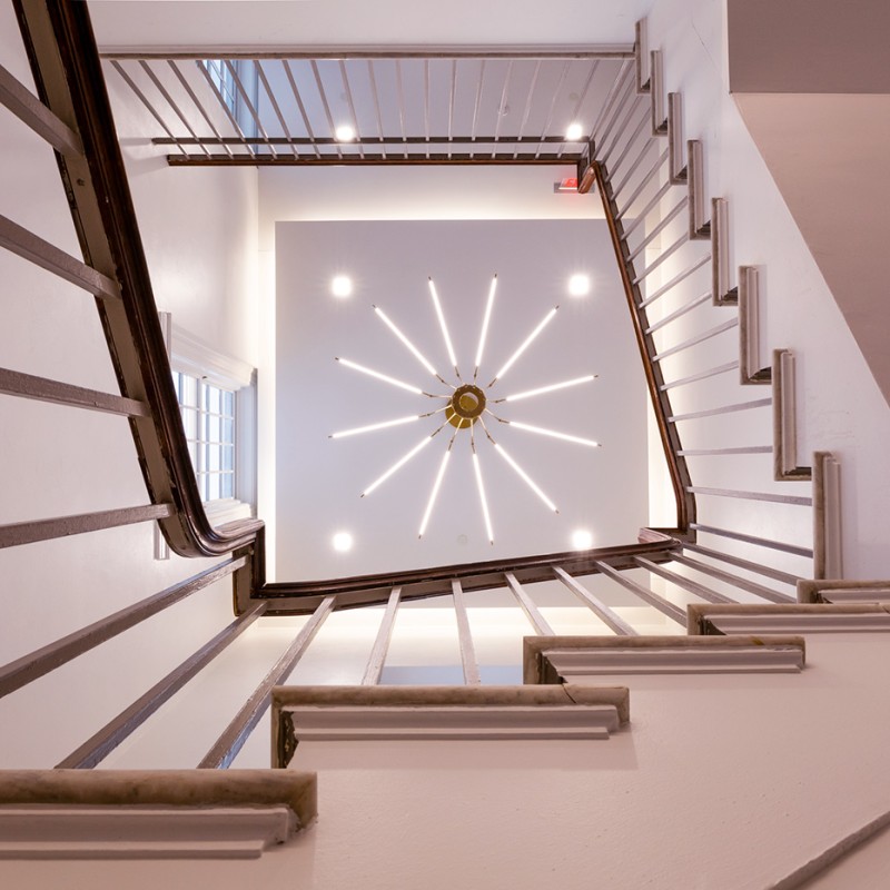 view up through a spiral staircase to a radiating light fixture