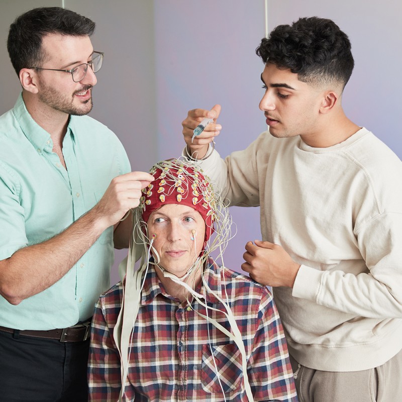 a professor and student attach an eeg cap with wires to a subject