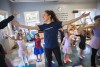 young woman leads children in ballet class