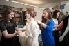students and professor dressing a mannequin in a white dress