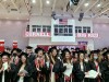 row of graduates in caps and gowns standing and clapping